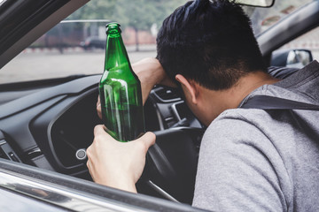 man driving with beer bottle in hand