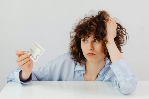 stressed woman looking at five dollar bill